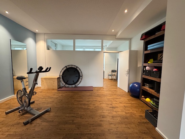 Trainingsraum für aktive Physiotherapie mit Ergometer, Trampolin und Therapiematerialien